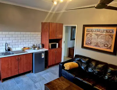 a living room with a couch and a kitchen at Highveld Guesthouse in Centurion