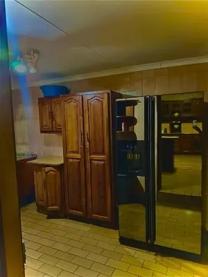 a kitchen with wooden cabinets and a black refrigerator at Wayside Guesthouse in Witbank
