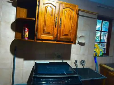 a kitchen with wooden cabinets and a sink at Wayside Guesthouse in Witbank