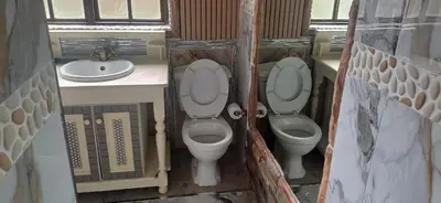 a small bathroom with two toilets and a sink at Wayside Guesthouse in Witbank