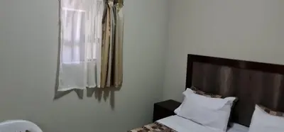 a bedroom with a bed and a window and a mirror at BINU motel in Secunda