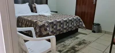 a bedroom with a bed and a white chair at BINU motel in Secunda