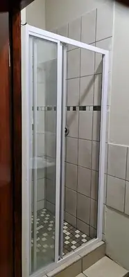 a shower with a glass door in a bathroom at BINU motel in Secunda