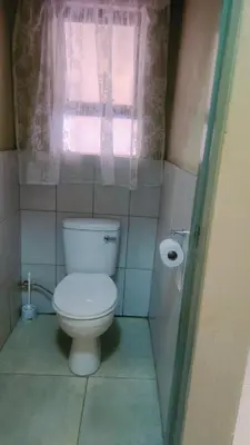 a bathroom with a white toilet and a window at BINU motel in Secunda