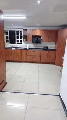 a large kitchen with wooden cabinets and a white tile floor at Beautiful Customized Hide Out in Centurion