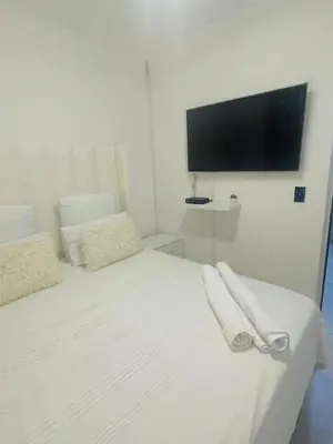 a white bed with two towels on it with a flat screen tv at HMT Modern House in Centurion
