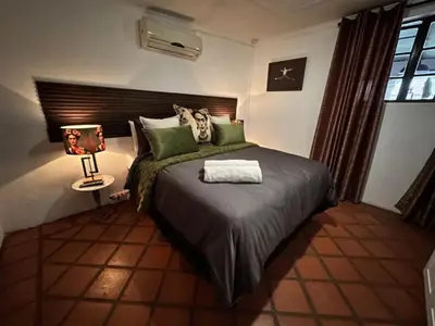a bedroom with a bed with green pillows and a lamp at Villa 21 in Pretoria