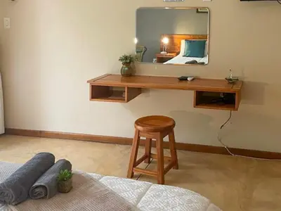a bedroom with a desk with a mirror and a stool at Hazyhaven Guest House in Hazyview