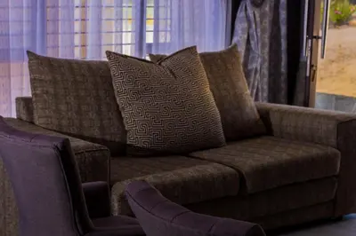 a brown couch with pillows sitting in a living room at Thulamahashe Guest farm in Thulamahashi