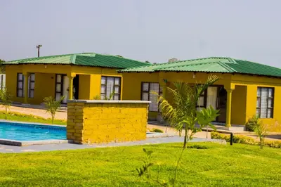 a yellow house with a green roof and a pool at Thulamahashe Guest farm in Thulamahashi