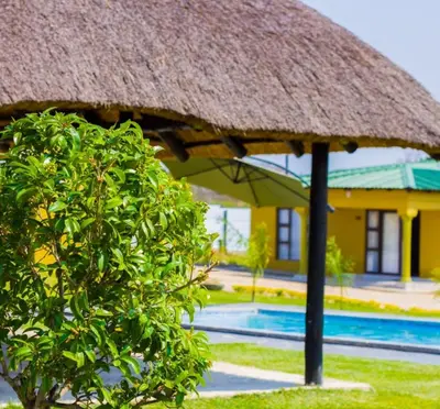 a resort with a thatched roof and a swimming pool at Thulamahashe Guest farm in Thulamahashi