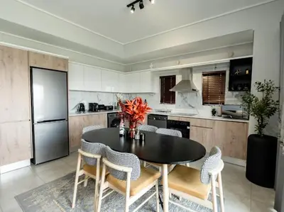 a kitchen with a table and chairs and a refrigerator at 347 Waterfall Penthouse in Midrand