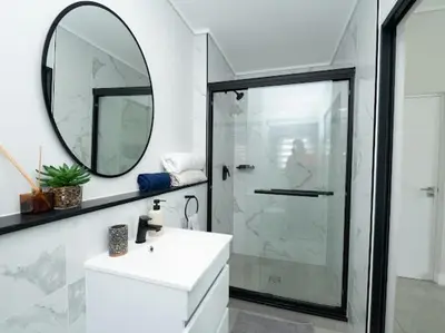 a bathroom with a shower and a sink and a mirror at 347 Waterfall Penthouse in Midrand