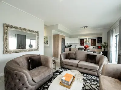 a living room with two couches and a table at 347 Waterfall Penthouse in Midrand