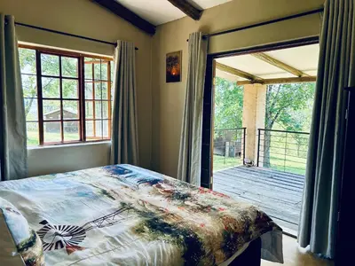 a bedroom with a bed and a door to a deck at The Windmill Country Retreat in Hazyview