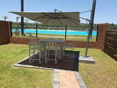 a table and chairs under an umbrella next to a pool at The Blyde lagoon facing Pretoria in Pretoria