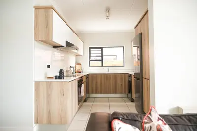 a kitchen with wooden cabinets and a couch in a room at The Blyde lagoon facing Pretoria in Pretoria
