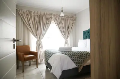 a bedroom with a bed and a chair and a window at The Blyde lagoon facing Pretoria in Pretoria