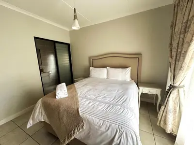 a bedroom with a bed with white sheets and pillows at The Blyde lagoon facing Pretoria in Pretoria