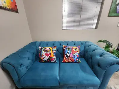 a blue couch with two colorful pillows on it at Ode to Serenity Cottage in Pretoria