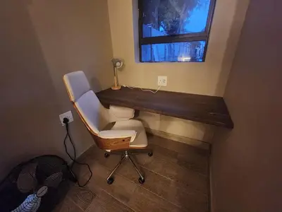 a desk and a chair in a room with a window at Ode to Serenity Cottage in Pretoria