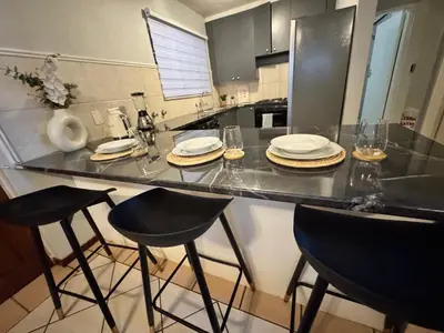 a kitchen with a counter with chairs and plates on it at Centurion La Creme Apartment II in Centurion