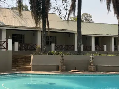 a house with a swimming pool in front of a house at Georges Valley Lodge in Tzaneen