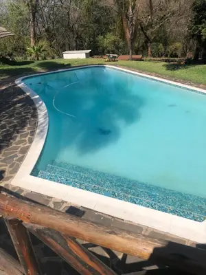 a swimming pool with blue water and a wooden table at Georges Valley Lodge in Tzaneen