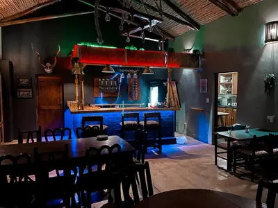 a dining room with tables and chairs and a bar at Georges Valley Lodge in Tzaneen