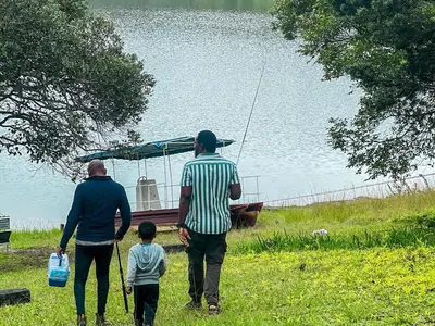 two adults and a child walking towards a boat on the water at Kruger Island Resort in White River