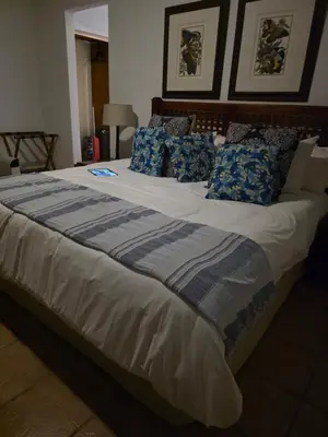 a large bed with blue and gray pillows on it at Kruger Island Resort in White River
