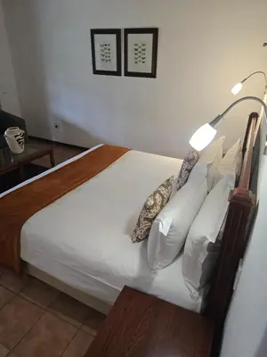 a bedroom with a bed with white sheets and pillows at Kruger Island Resort in White River