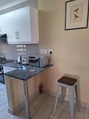 a kitchen with a counter with a microwave and a stool at Bustani 1 Self Catering Studio Minimum 2 Nights in Edenvale