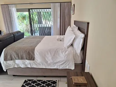 a bedroom with a bed with white sheets and pillows at Bustani 1 Self Catering Studio Minimum 2 Nights in Edenvale