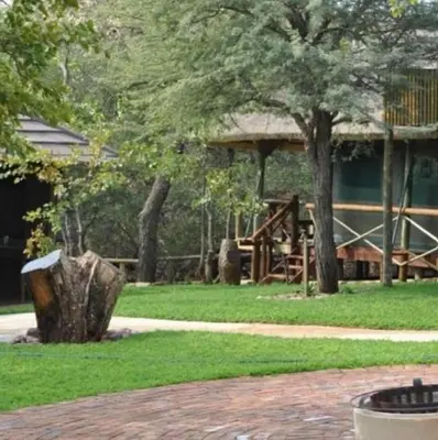 a park with a tree stump and a playground at Sunset Game Farm in Mopane