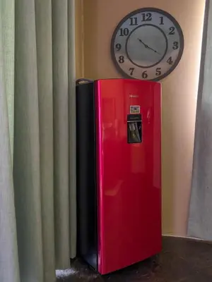 a red refrigerator next to a clock on the wall at Spies Villa - Fast Wi-fi, Netflix, DSTV, Solar, Certified Water System in Middelburg