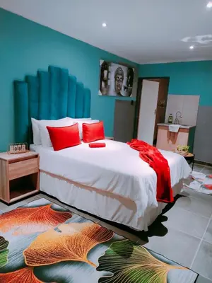 a bedroom with a large bed with red pillows at Reutlwane Gardens B&B in Secunda