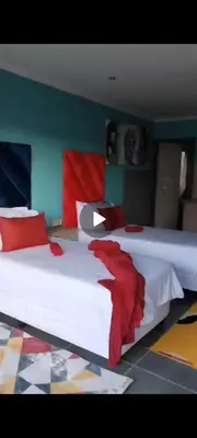 a bedroom with two white beds with red pillows at Reutlwane Gardens B&B in Secunda