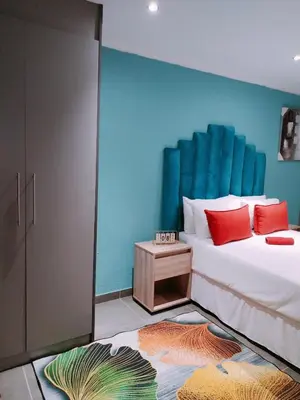a bedroom with a bed with a blue wall at Reutlwane Gardens B&B in Secunda