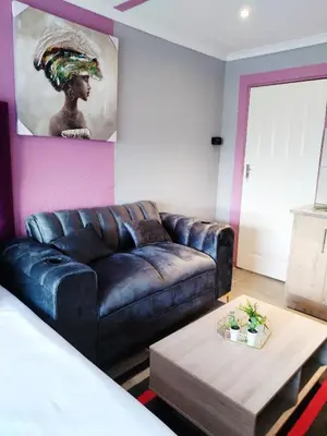 a living room with a leather couch and a coffee table at Reutlwane Gardens B&B in Secunda