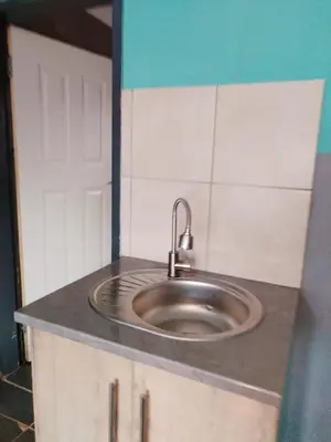 a kitchen counter with a sink in the middle at Reutlwane Gardens B&B in Secunda