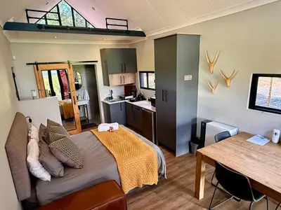 a bedroom with a bed and a table and a kitchen at Spasie 30 Harties in Hartbeespoort