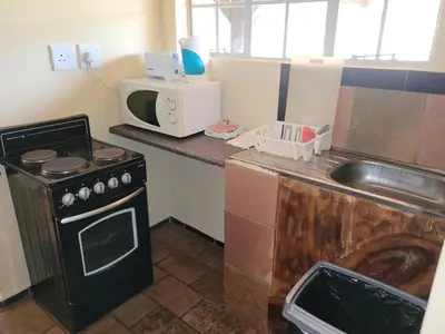 a small kitchen with a stove and a microwave at Lush Horizons Game Lodge in Modimolle