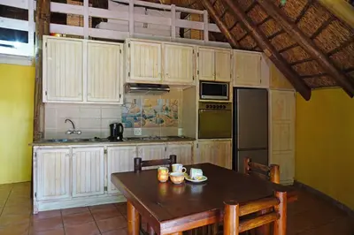 a kitchen with wooden cabinets and a wooden table at Thaba Pitsi Safari Lodge in Bela-Bela