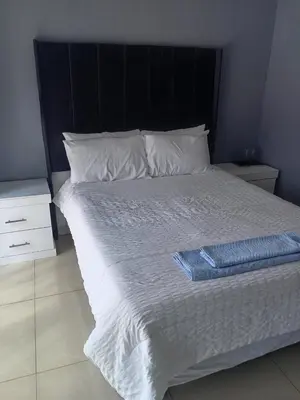 a white bed with a black headboard and white pillows at Crystal Park Guest house in Benoni