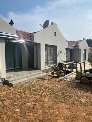 a white house with a brick patio in front of it at Crystal Park Guest house in Benoni