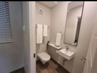 a white bathroom with a toilet and a sink at The Blyde lagoon Penthouse in Pretoria