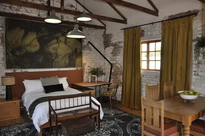 a bedroom with a bed and a table and a desk at The Upper Room in Polokwane
