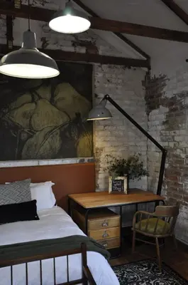 a bedroom with a bed and a desk and two lights at The Upper Room in Polokwane