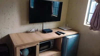 a television on top of a wooden stand with a microwave at Eleven on Coulbrough in Midrand
